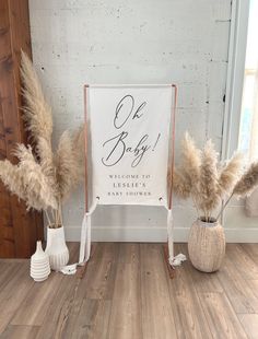 two white vases with dry grass in front of a sign that says, one baby