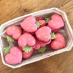 a box filled with pink frosted strawberries on top of a wooden table