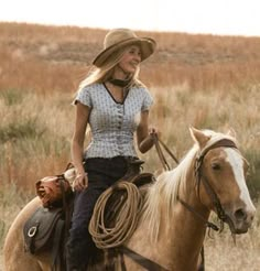 a woman riding on the back of a brown horse in a dry grass covered field