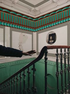 a person standing on the top of a stair case next to a green and white wall