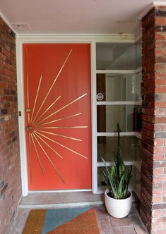 a red door with gold lines on it and a potted plant in front of it