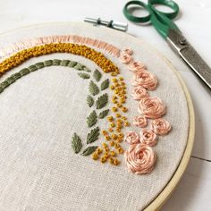 a close up of a embroidery on a table next to scissors and yarn with flowers