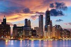 the city skyline is lit up at night, with skyscrapers in the foreground