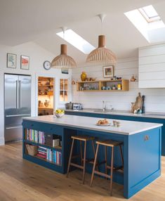 an open kitchen with blue island and white counter tops, two pendant lights over the sink