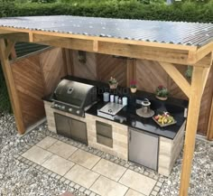 an outdoor kitchen with grill, sink and potted plants