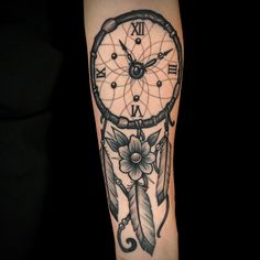 a tattoo with a clock and feathers on it's arm that says dream catcher