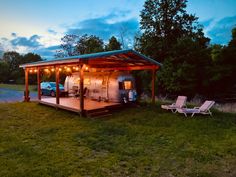 a car is parked in front of a covered area with lawn chairs and lights on it