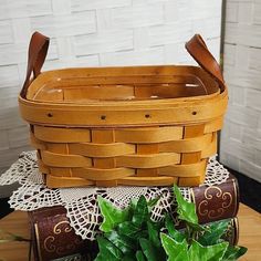 a wooden basket sitting on top of a table next to a potted green plant