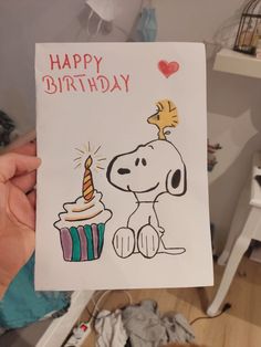 a person holding up a birthday card with a dog and cupcake on it's side