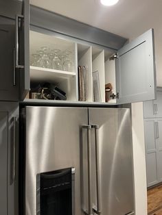 a stainless steel refrigerator and freezer combo in a kitchen with wood floors, cabinets and shelves