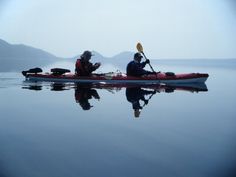 two people in kayaks paddling on calm water