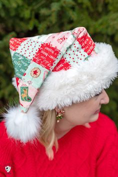 a woman wearing a red sweater and white fur hat with christmas decorations on it's brim