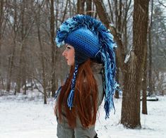 a woman with long red hair wearing a blue knitted hat and holding a snowboard