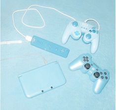 two video game controllers sitting next to each other on a blue blanket with cords attached