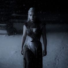 a woman standing in the snow at night with her hands on her hips and looking off into the distance