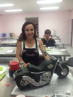 a woman sitting on top of a motorcycle in a room filled with tables and desks