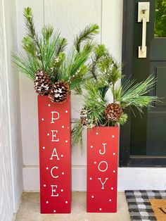 two red vases filled with pine cones and evergreen branches sitting on the front porch