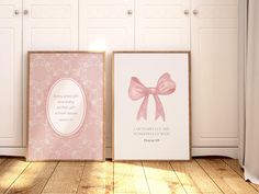 two framed pictures with pink bows are sitting on the floor in front of white closet doors