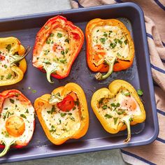 six stuffed bell peppers on a baking sheet with cheese and herbs in the middle, ready to be cooked