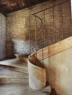 there is a spiral staircase in an old building with brick walls and exposed wood flooring