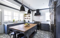 a kitchen with black and white tile flooring and wooden counter tops on the island