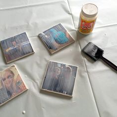 some pictures are sitting on a table with a brush and paint bottle next to them