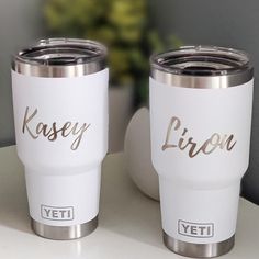 two personalized yeti tumblers sitting on top of a white table next to each other