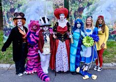 a group of people dressed up in costumes posing for a photo on the side walk