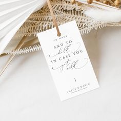 a close up of a tag on a table with flowers and feathers in the background