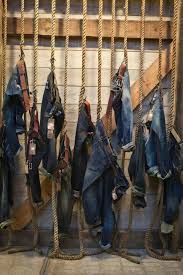 several pairs of jeans hanging on ropes