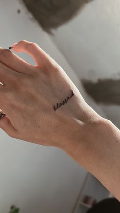 a woman's hand with a small tattoo on her left wrist that says, love