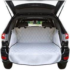 the back end of a car with its trunk open and it's bed covered in white fabric