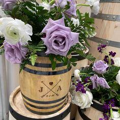 purple and white flowers are in a wooden barrel