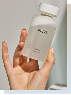 a person holding up a white bottle with the word flow on it's side