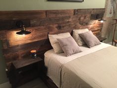 a bed that has some pillows on top of it and two lights above the headboard