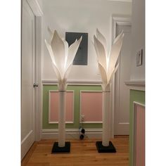 two tall white lamps sitting on top of wooden floors