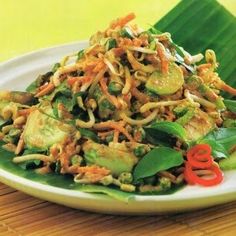 a white plate topped with food on top of a wooden table next to green leaves