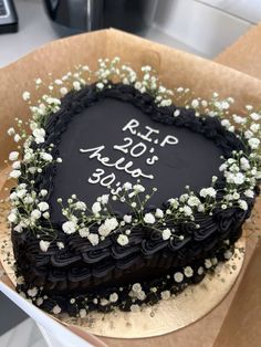 a heart shaped black cake with white flowers on it that says rip 90 % off