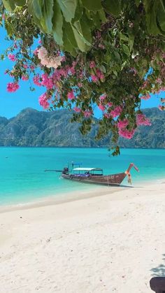 a boat that is sitting in the sand near the water and some people on it