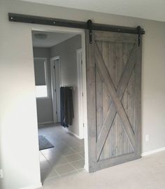 an open sliding door in the middle of a room with tile flooring and white walls