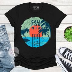 California retro style surf shirt. Vintage Palm trees and the beach. Perfect for wearing at the beach, fishing, surfing, boating or just living the dream. Surf Tee Design, Retro Surfing T-shirt For Beach Season, Graphic Print T-shirt For Summer Vacation, Surfing Graphic Tee With Screen Print, Graphic Surfing T-shirt With Screen Print, Graphic Tee With Screen Print For Surfing, Graphic Tee T-shirt With Front Print For Surfing, Surfing Short Sleeve T-shirt With Sublimation Print, Graphic Print Surfing Shirt