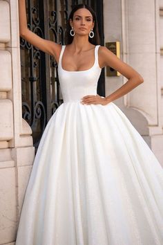 a woman in a white wedding dress posing for the camera with her hand on her hip