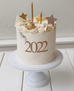 a white cake with gold stars and numbers on it sitting on top of a plate