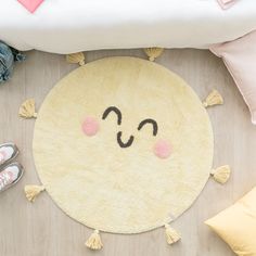 a yellow rug with a smiley face drawn on it next to some shoes and pillows