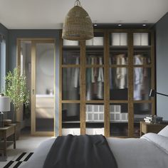 a bedroom with blue walls and white bedding has an open glass door leading to the closet