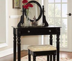 a black vanity table with a mirror and stool in front of the door, on top of a rug