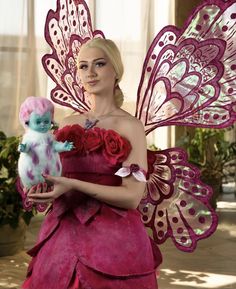 a woman dressed as a fairy holding a doll