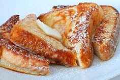 two pieces of french toast on a white plate with powdered sugar and butter sprinkled on top