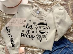 two sweaters with the words let it snow on them and a hat next to each other