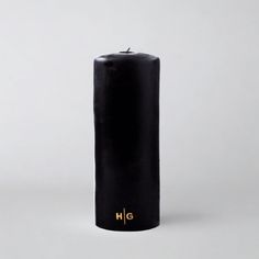 a black candle with the word wlc written on it and gold lettering is in front of a white background